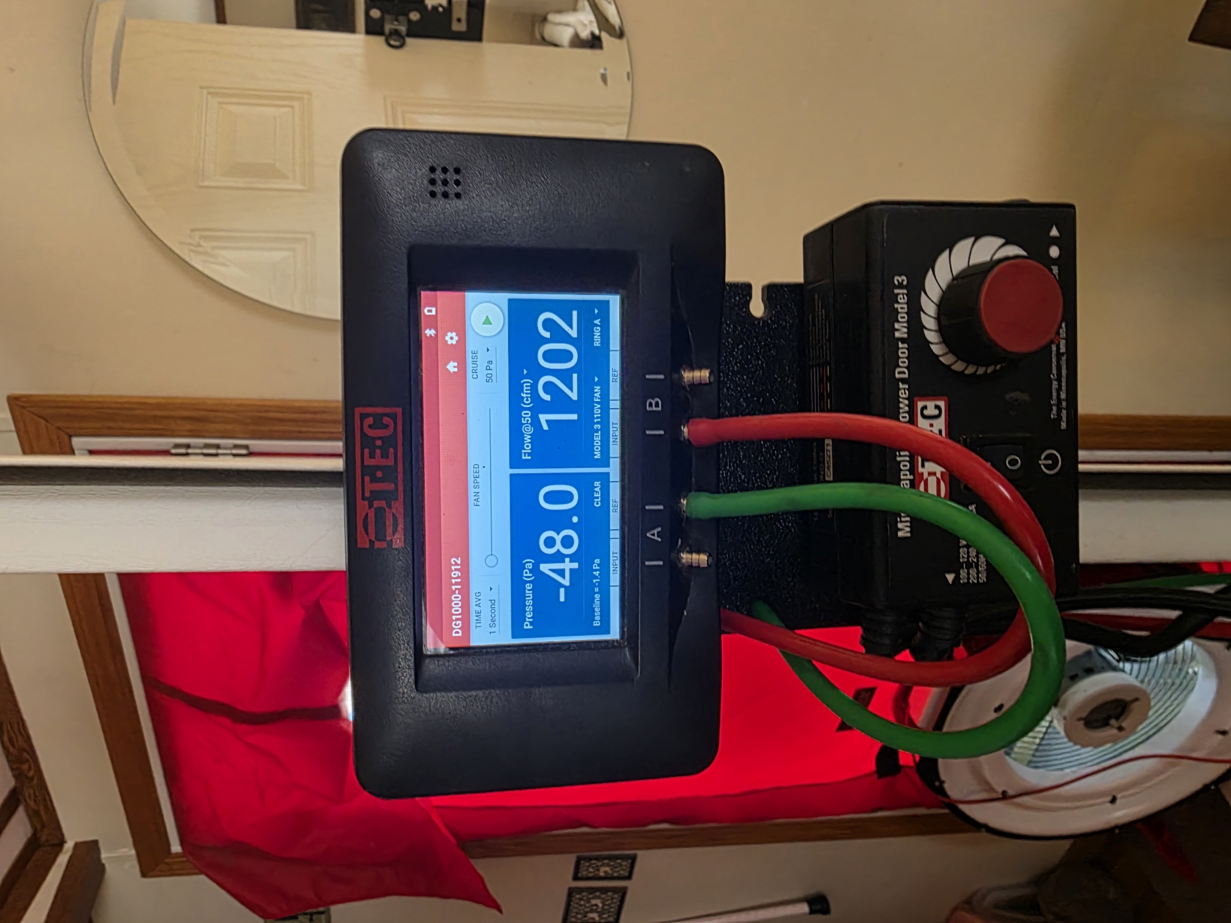 Blower door test equipment measuring home air leakage during a weatherization assessment