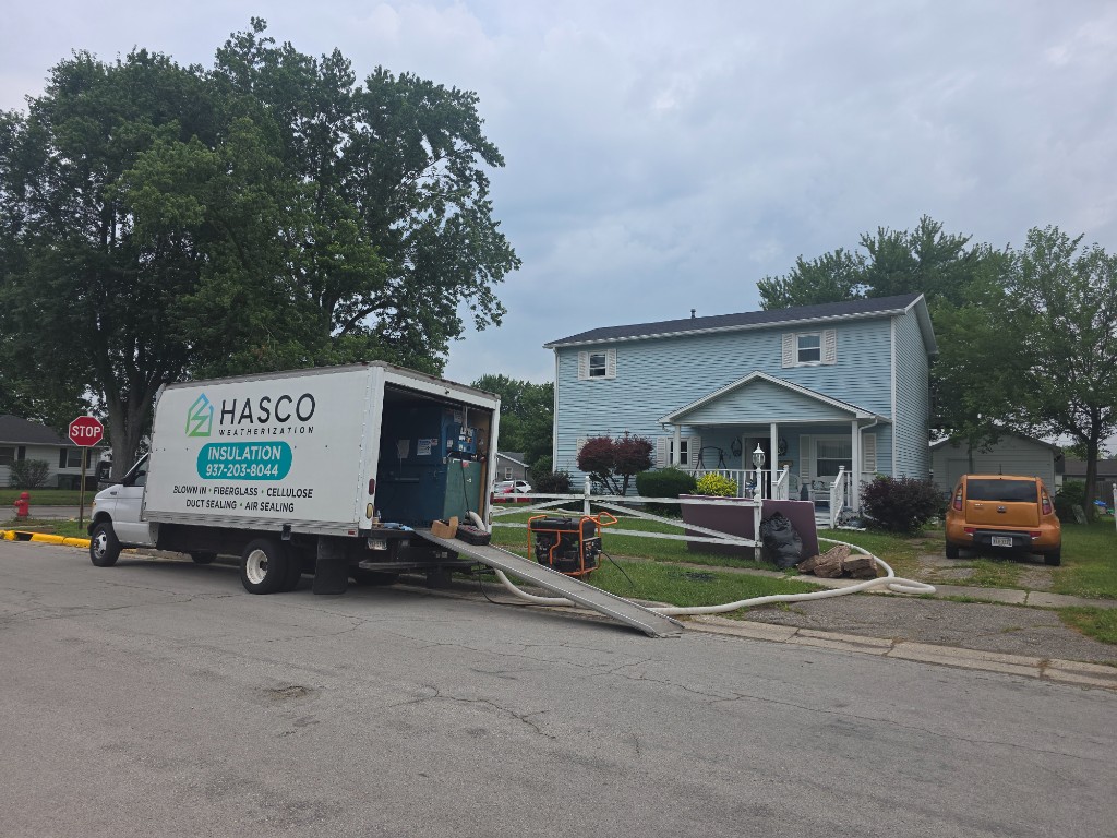 HASCO Weatherization box truck in front of a light blue two-story home