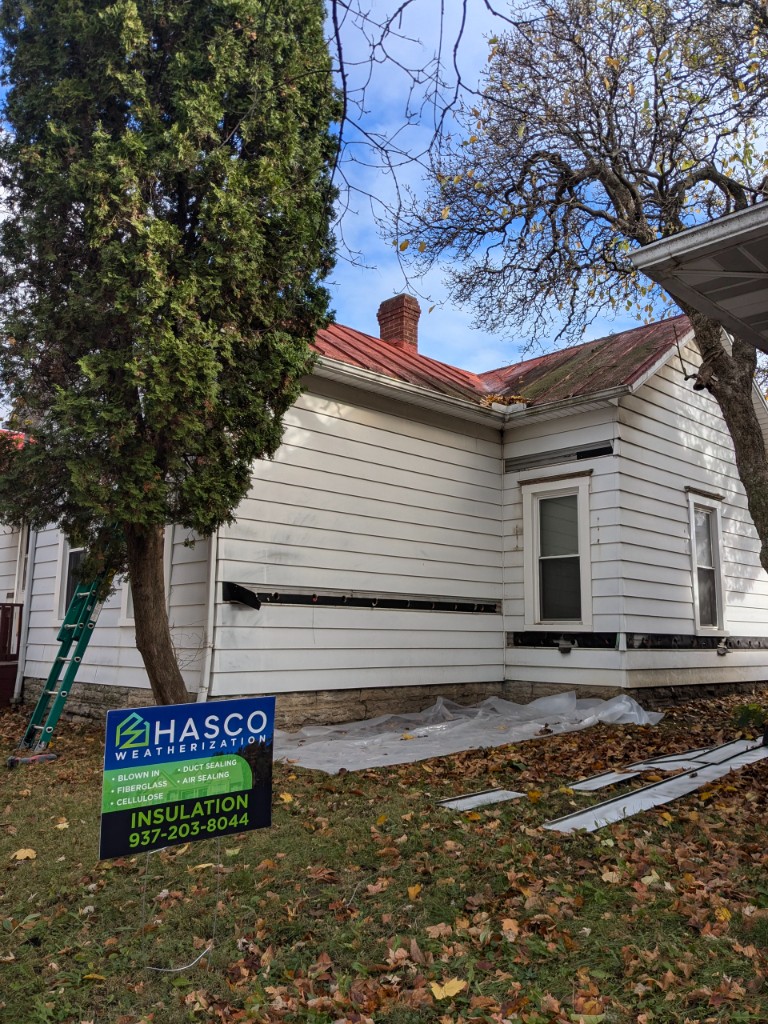HASCO Weatherization yard sign in front of a home with siding removed for exterior wall insulation
